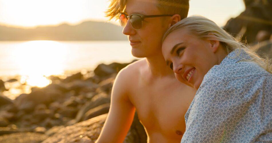 Chłopak i dziewczyna przytulają się, podziwiając zachód słońca nad wodą
